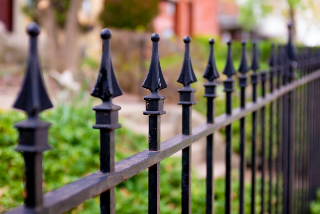 Premium black powder-coated aluminum fence panels in a residential yard with greenery
